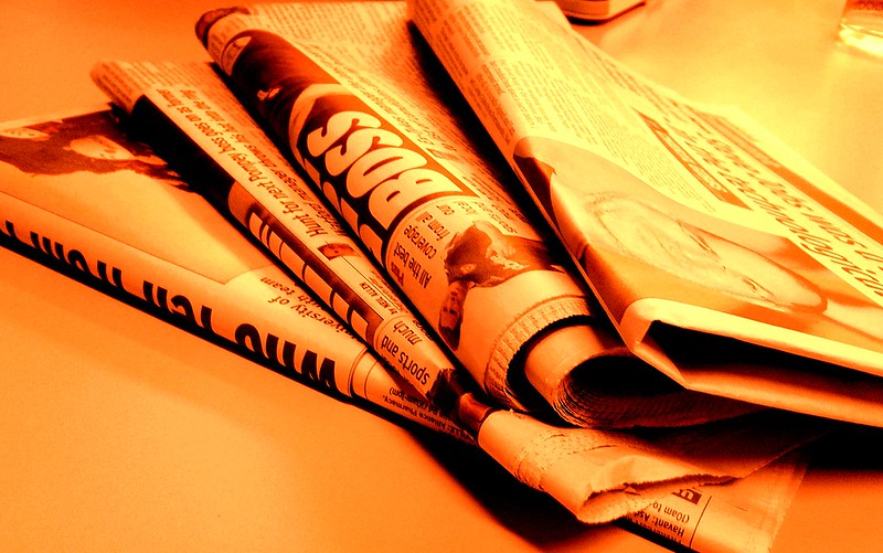 A photo of newspapers with an orange light filter applied