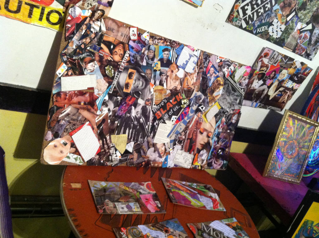 Photo of a large collage, propped up on a table and surrounded by other smaller works of collage.