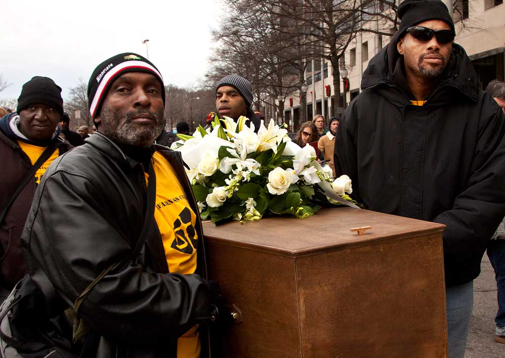 Four people carry a coffin