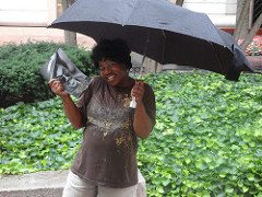 Vendor Sybil Taylor holding an umbrella and a memorial photo of Chuck Brown