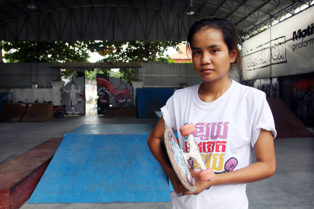 Cambodian girl holding skateboard.