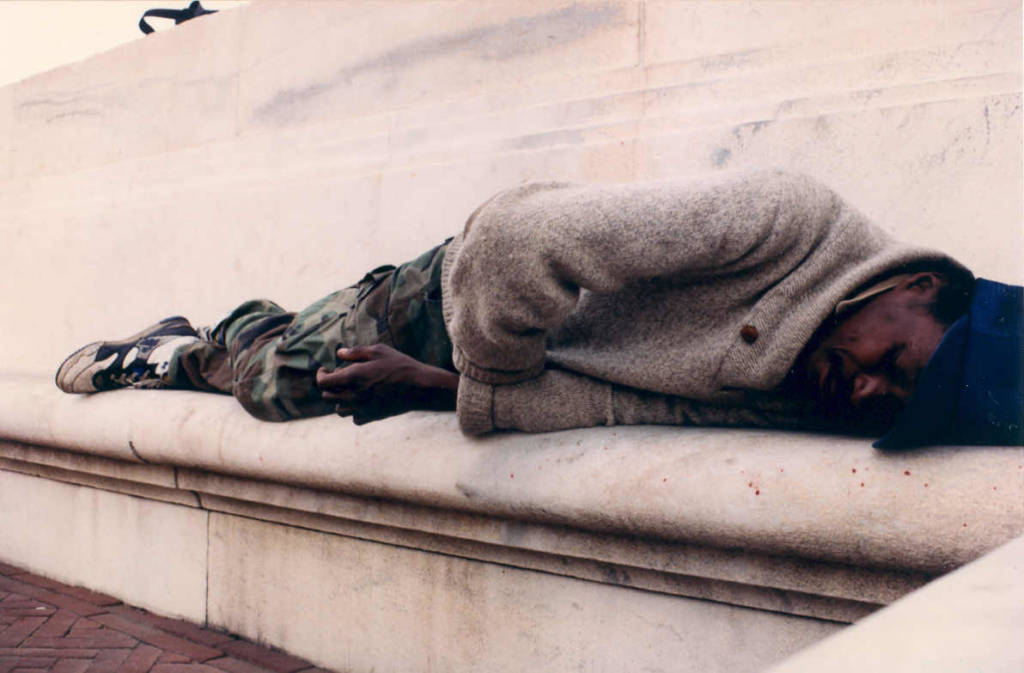 Homeless man laying on a bench outside Union Station