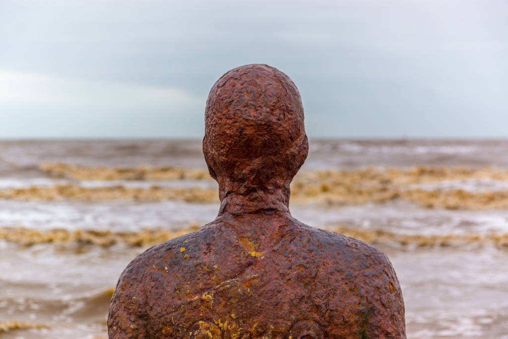 An iron statue looks at the horizon.