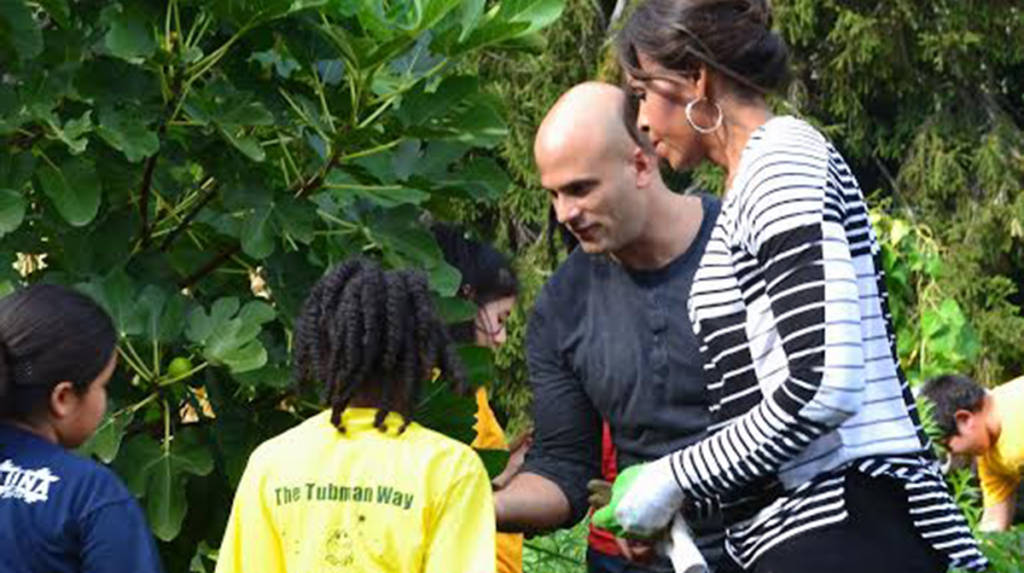 a photo of Sam Kass and Michelle Obama showing the students figs they had just taken from the fig tree