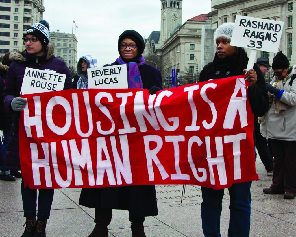 Activists display a handmade bright red banner in Freedom Plaza, DC that reads "Housing is a Human Right."