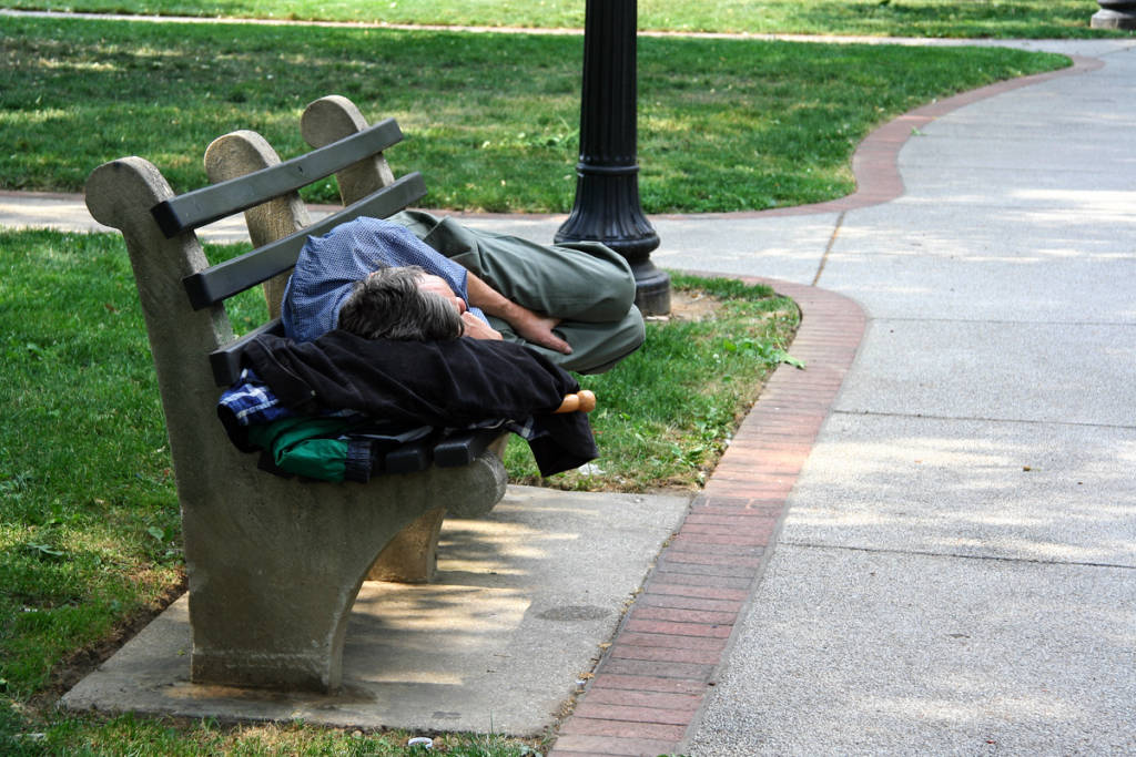 Homeless man sleeps on park bench