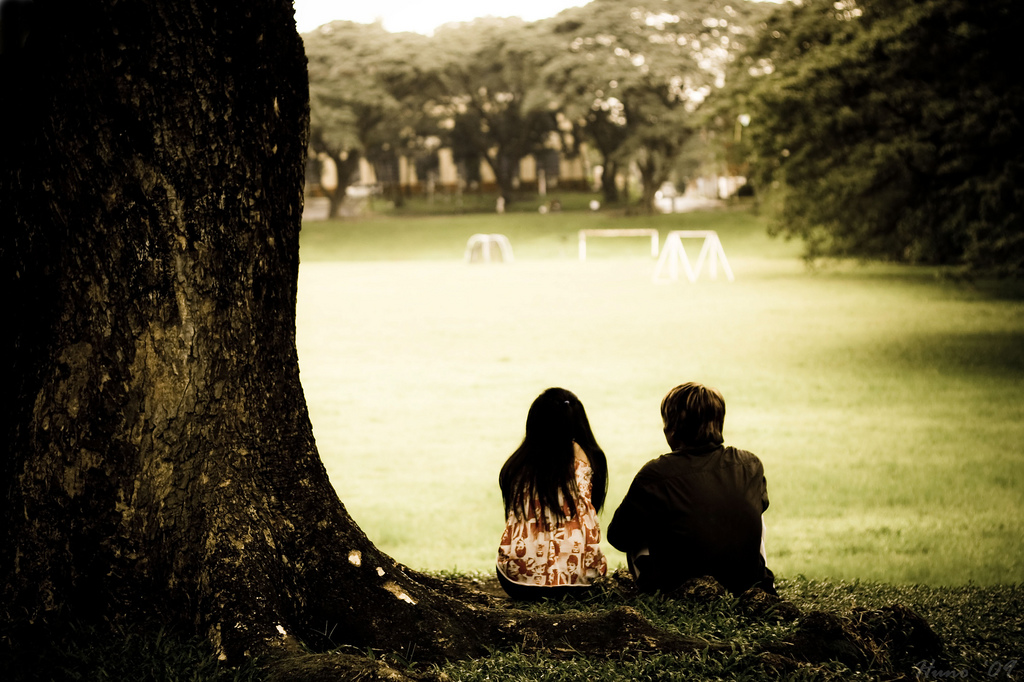 A couple sits under a tree