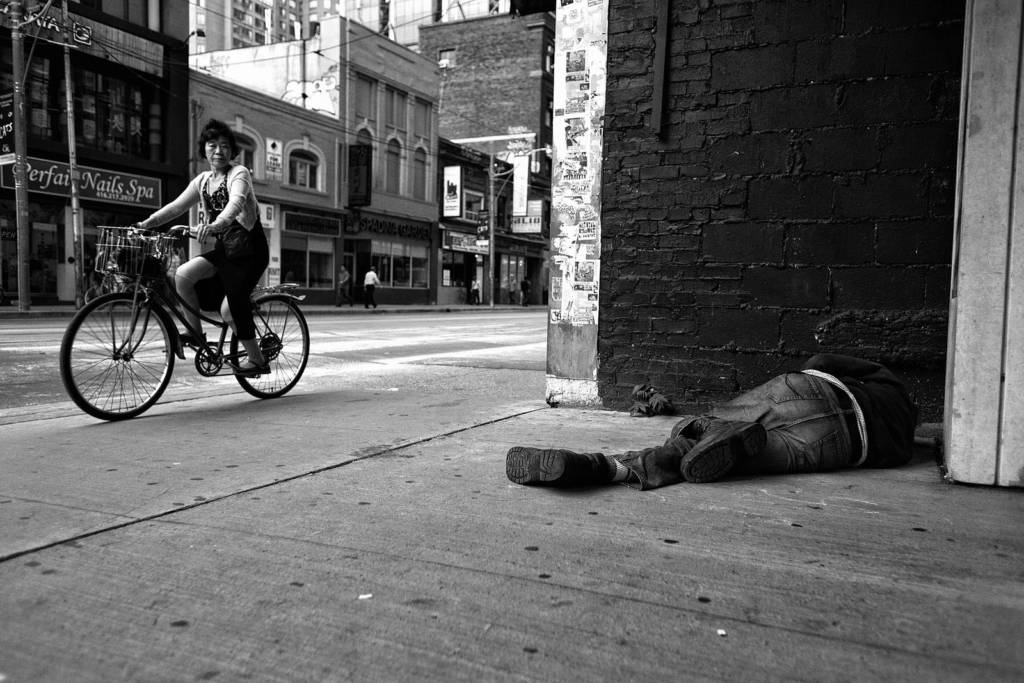 Bike riding past man sleeping on sidewalk