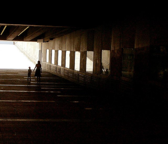 Image of a mother and child walking down a poorly-lit tunnel.