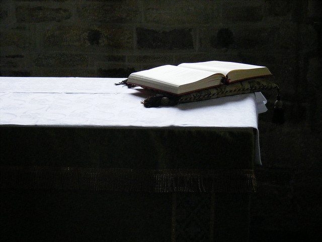 Image of a Bible on a table with a stream of light touching both.