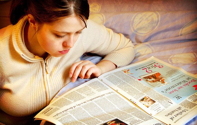 Photo of teenager reading a newspaper.