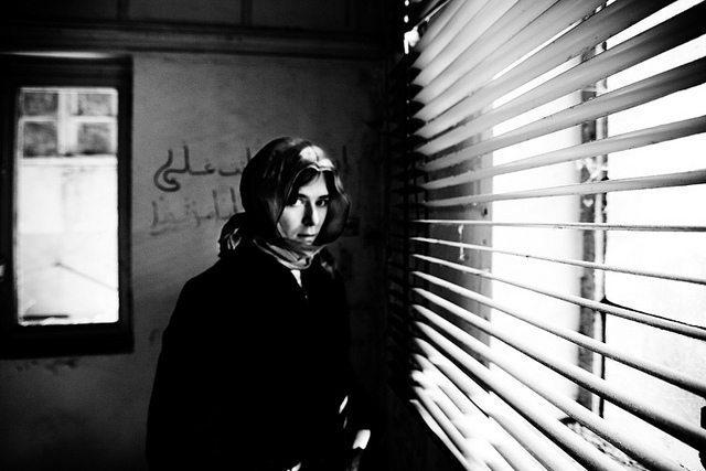 Image of a female refugee in front of a window.