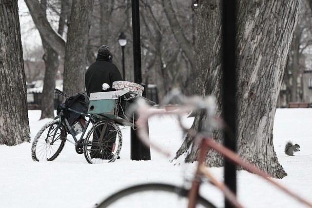A homeless man with his bike in the snow.