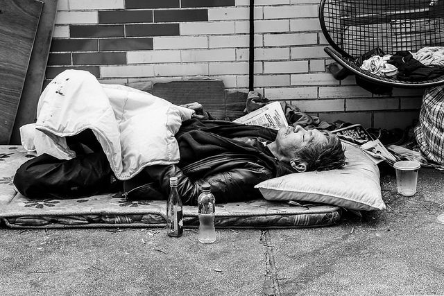 Image of a homeless man laying on the street.