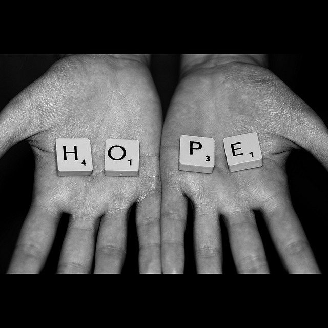 Image of two open hands with scrabble tiles that spell out, "Hope."