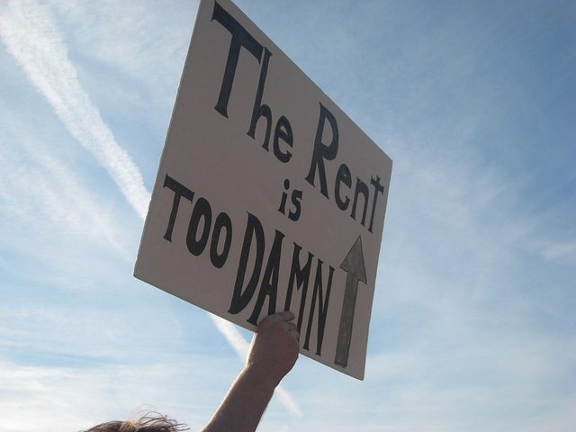 Image of a protest sign that says, "The rent is too damn high."