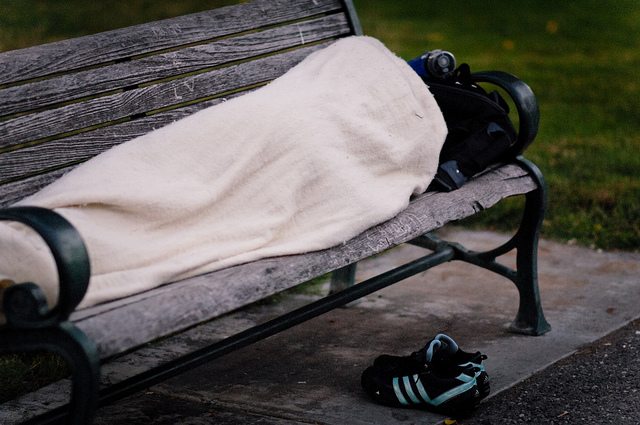 Image of a homeless individual sleeping on a bench.