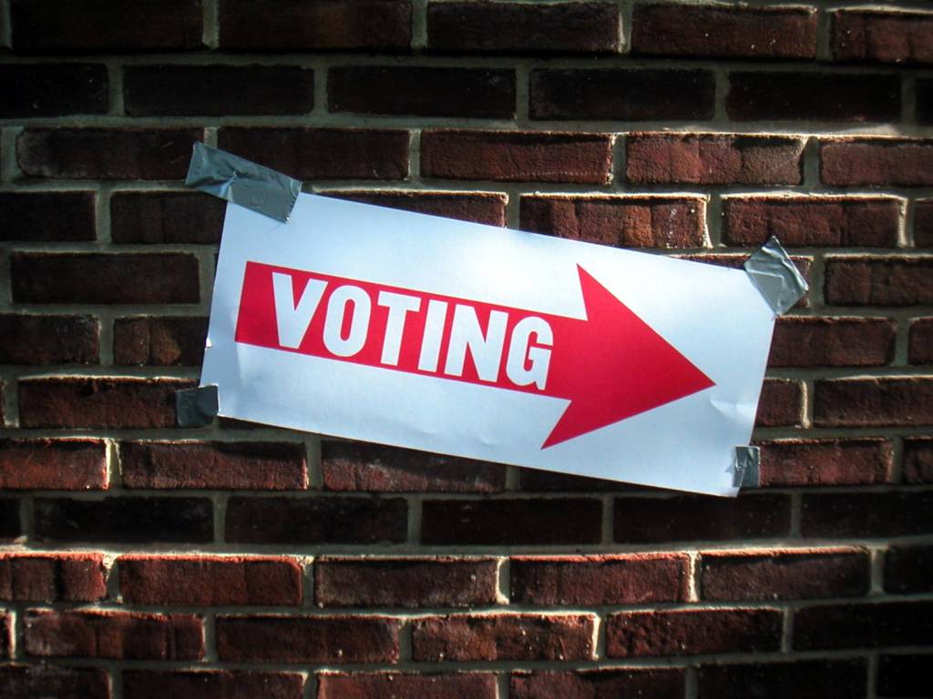 A "Voting" sign taped to a brick wall