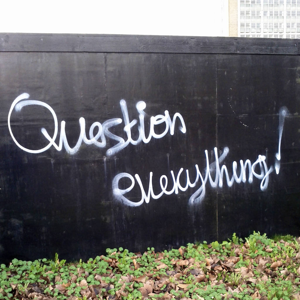 A wall spray painted with the phrase, "Question everything!"