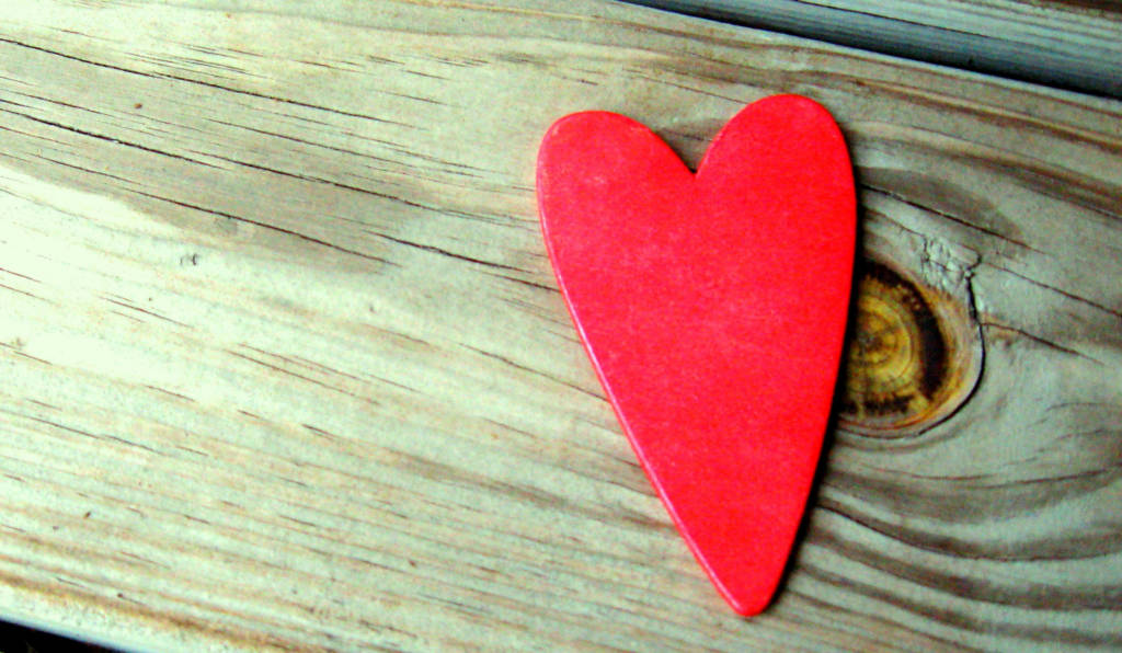 A red paper heart on a piece of wood.
