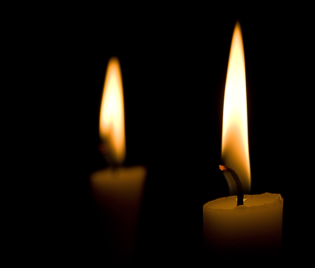 A picture of two candles burning in darkness.