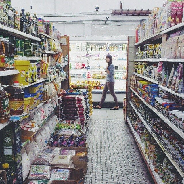 A grocery store aisle with a women walking through.