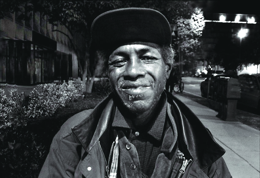 A black and white photo of Larry Avents standing on a D.C. street and smiling