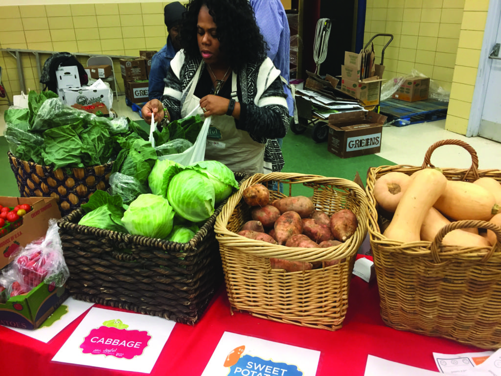 A Joyful Food Market volunteer distributes produce at Neval Thomas Elementary