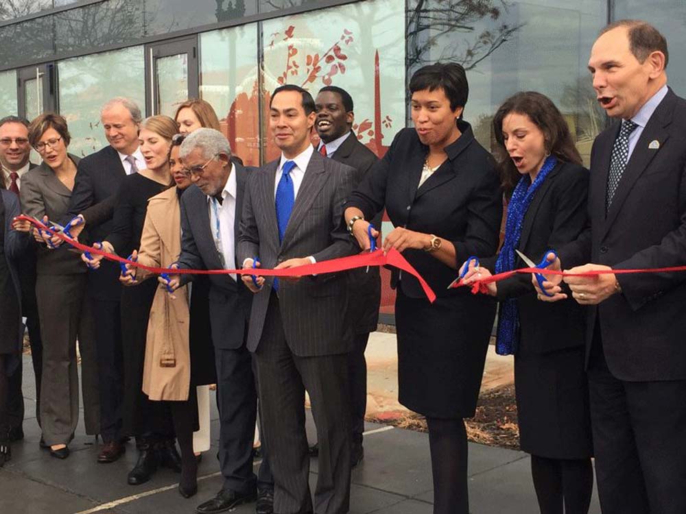 Laura Zeilinger of DC Human Services, Julian Castro of HUD, Mayor Muriel Bowser and others celebrate at the ribbon cutting
