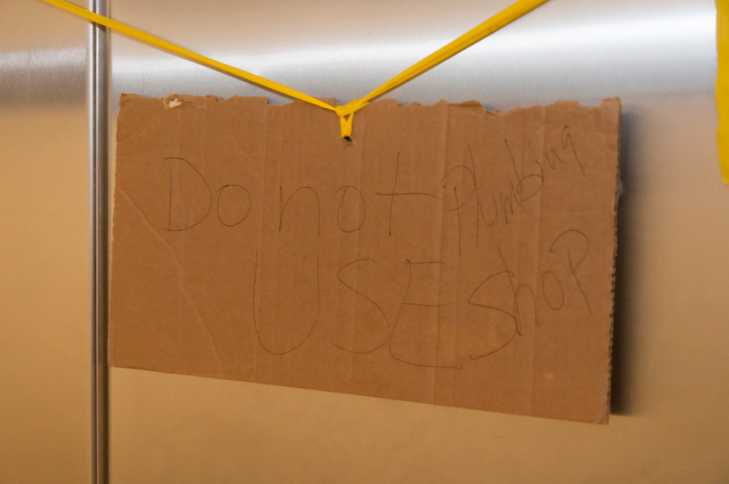 Cardboard sign with the handwritten message "Do not use Plumbing Shop" placed on a restroom stall inside the Jefferson Memorial.