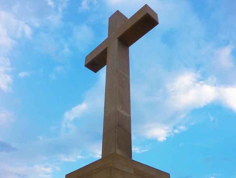 A cross against a blue sky and clouds.