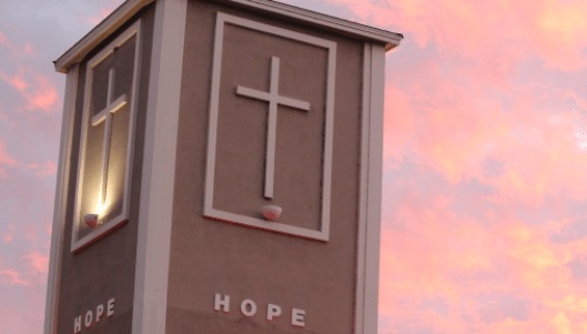 A church steeple with a cross and the word "hope"