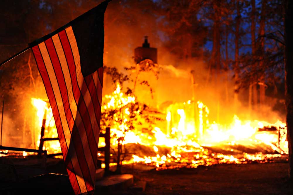 a photo showing a fire with an American flag in the foreground.