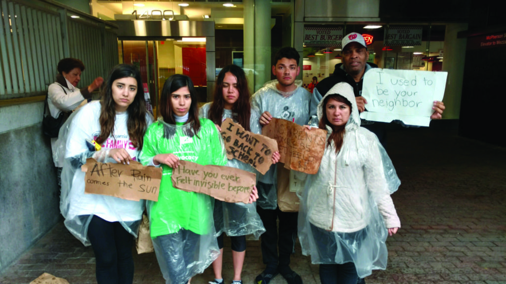 A photo of mexican teens holding signs about homelessness