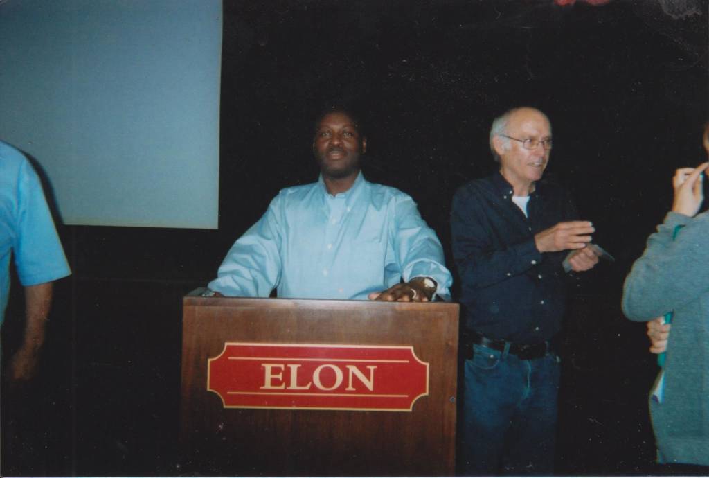 A photo of James Davis standing behind a podium labeled "Elon" with Michael Stoops next to him.