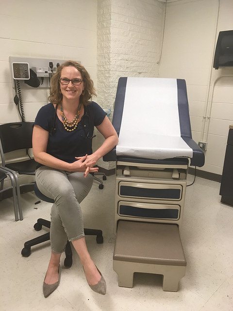 Courtney Pladsen next to a doctor's chair.