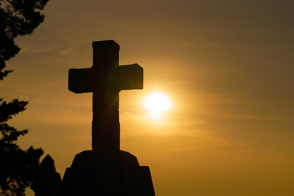 A photo of a cross during sunrise.