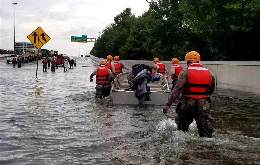 Hurricane relief workers push a boat up a flooded highway.
