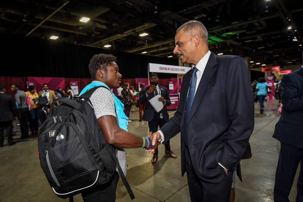 Eric Holder and a young job seeker shake hands