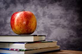An apple on top of three text books.