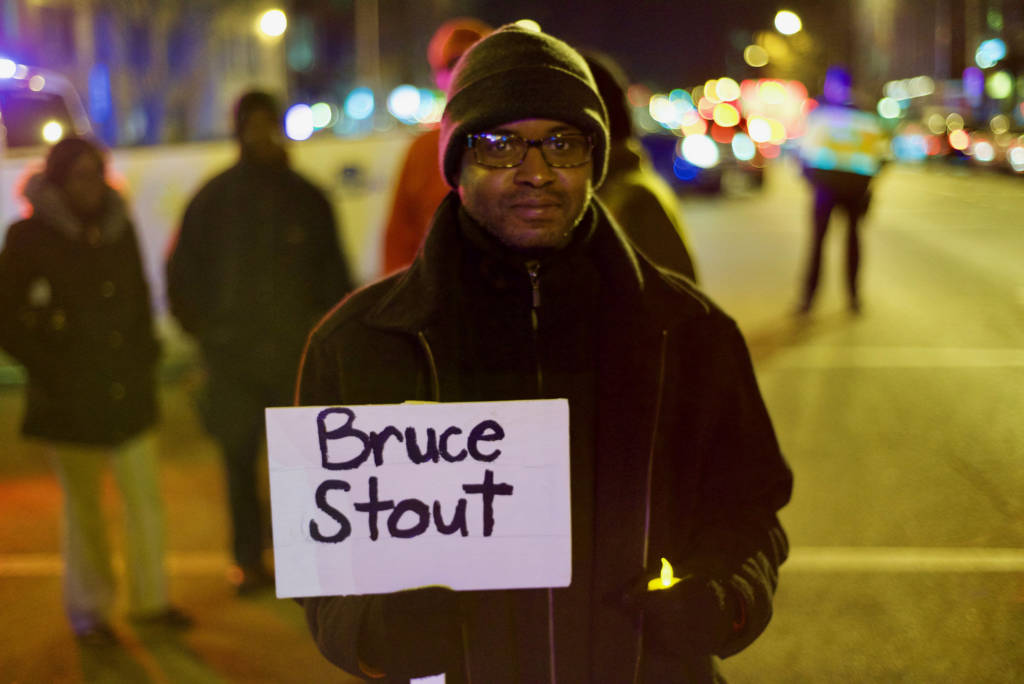 A man hold up a placard bearing the name "Bruce Stout" in a march to draw attention to the death of people experiencing homelessness.