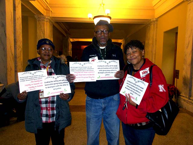 Three constituents who were at the vote hold signs urging the councilmembers to vote no.