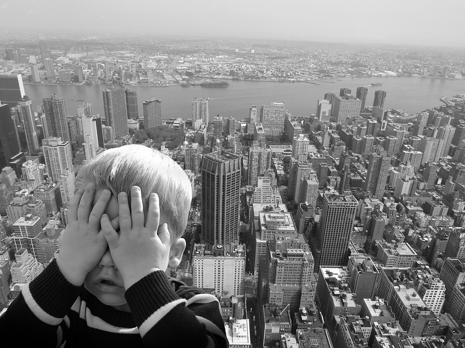 A child covering his eyes, fearing the heights.
