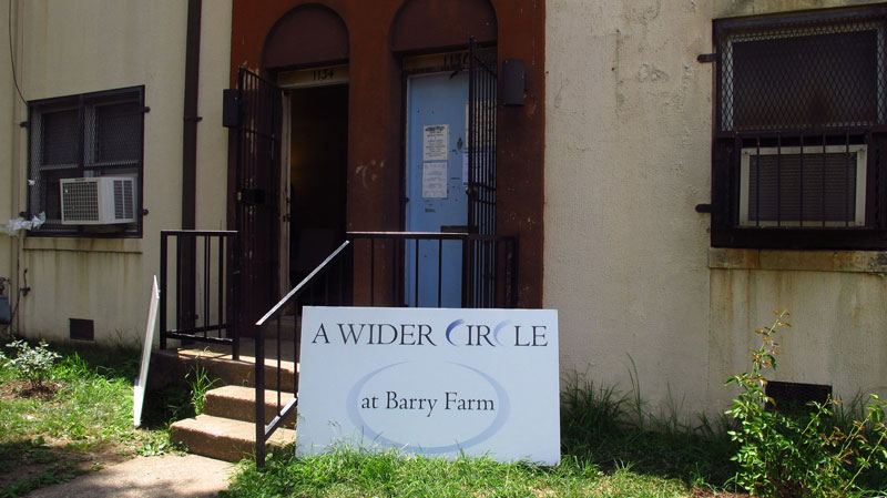 Photo of a house in Barry Farm with a sign in front of it that reads "A Wider Circle at Barry Farm"
