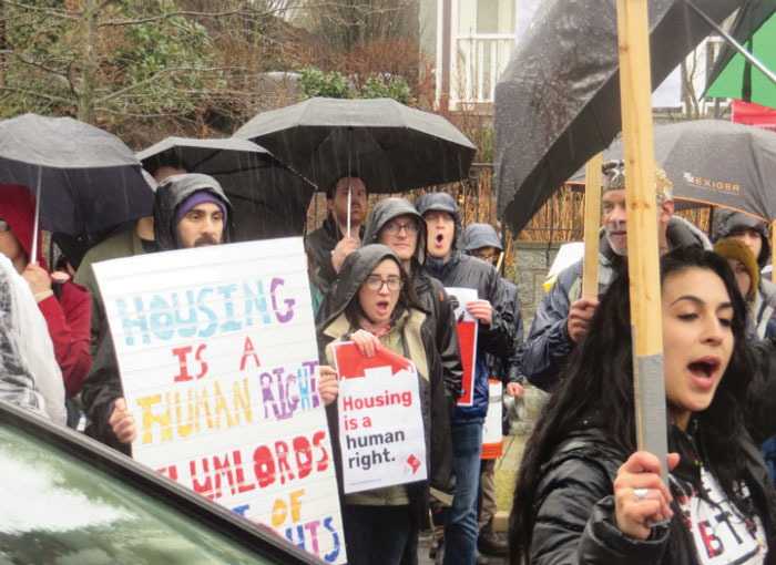 Photo of protesters holding signs marching in the rain.
