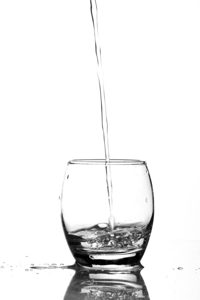 A waters bottle, out of scene, supling water to a glass.