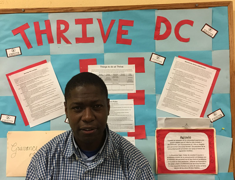Reginald Charlemagne stands in front of a bulletin board that reads "Thrive DC"