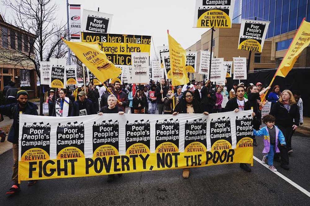 Photo of marchers carrying signs about poverty, love and justice.