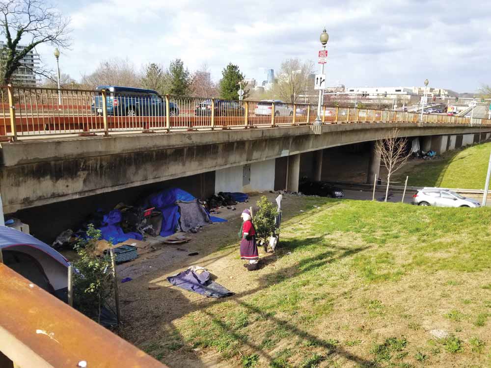 Photo of the K Street Bridge and several tents in under it in the foreground and the distance.
