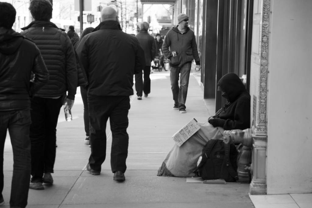 A homeless person being ignored by passersby.